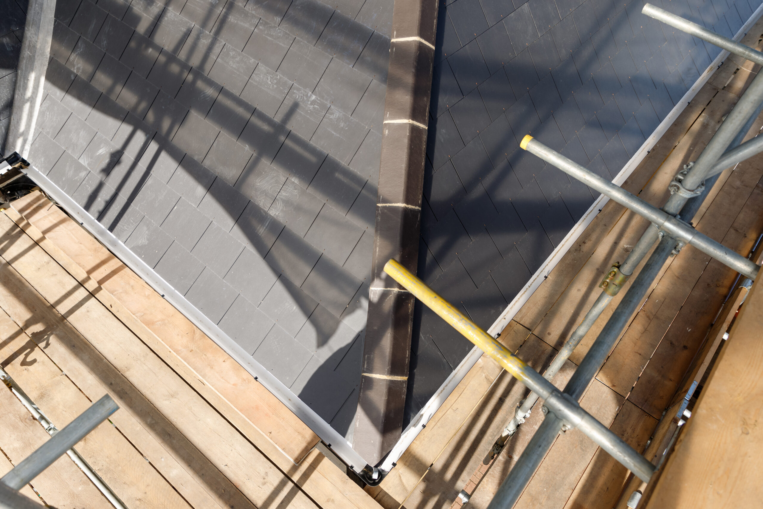 Close up of the corner of a newly tiled roof, showing scaffolding