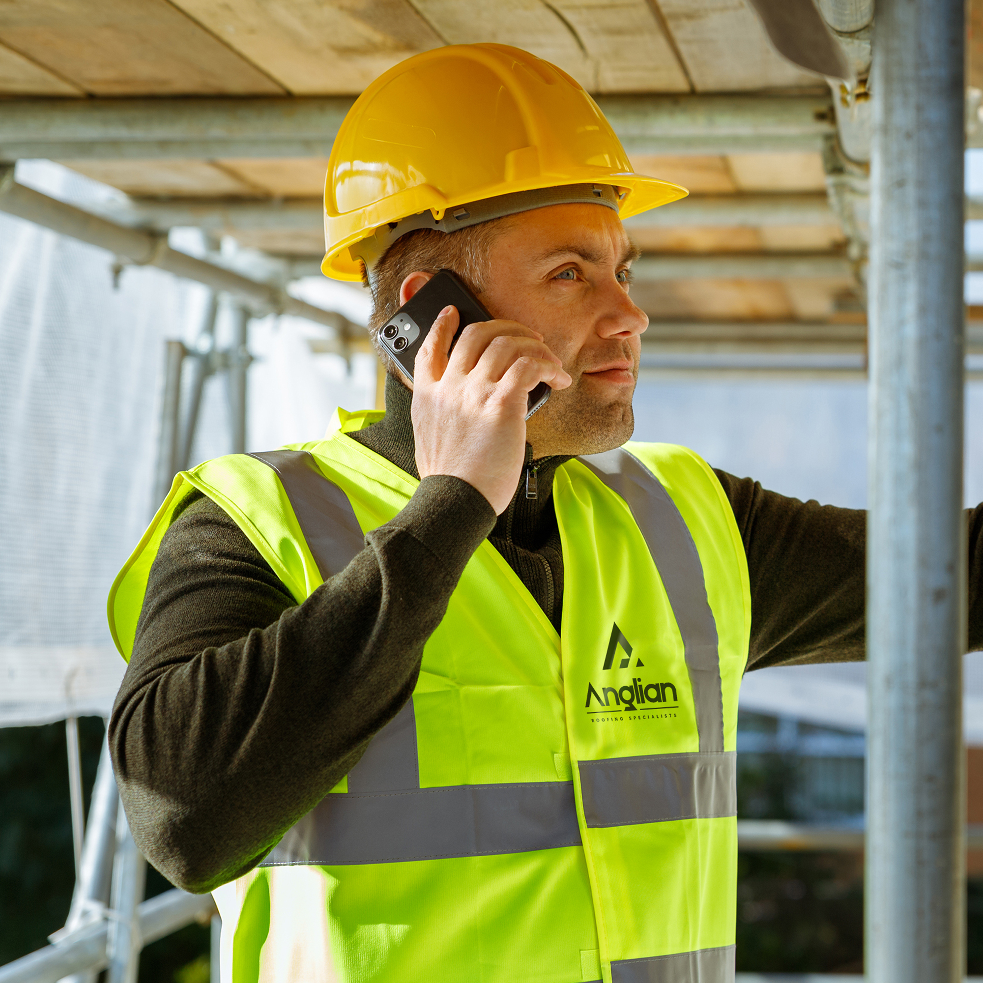 Anglian Roofing project manager surveying roofing work high up on scaffolding