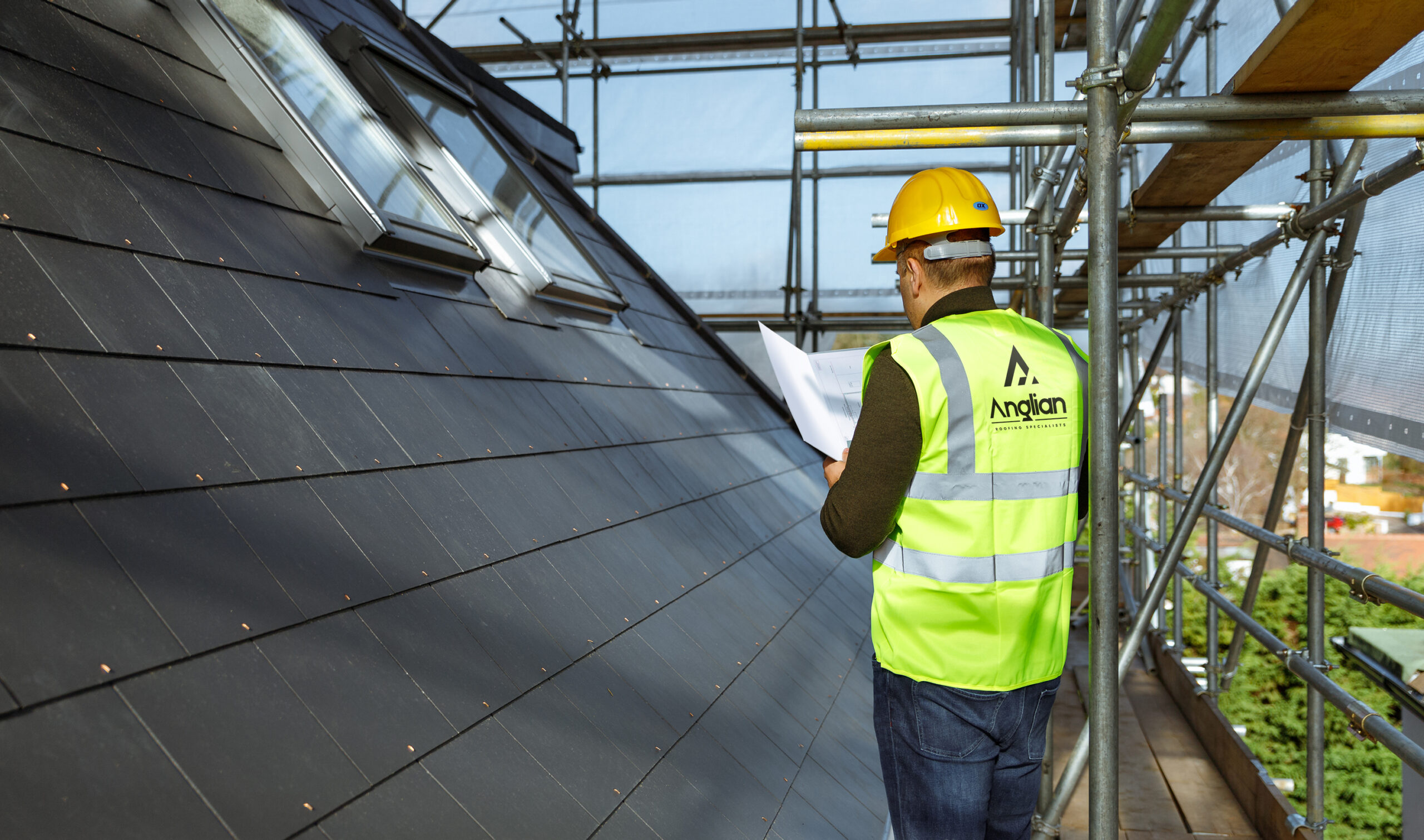 Anglian Roofing project manager surveying roofing work high up on scaffolding